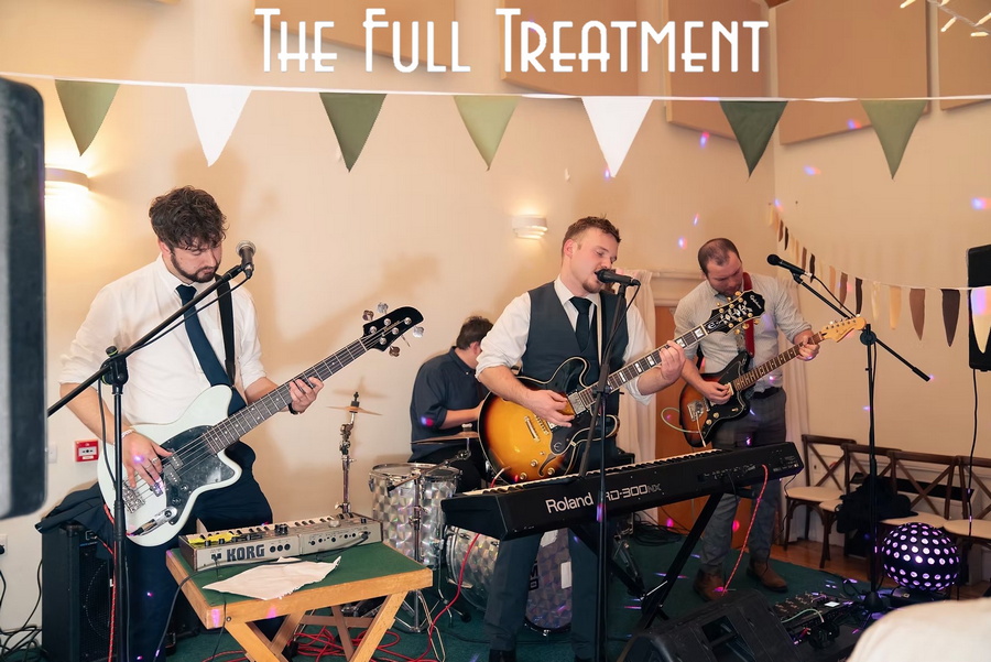 A picture of the 4 members of The Full Treatment band playing guitars, keyboard and drums and singing